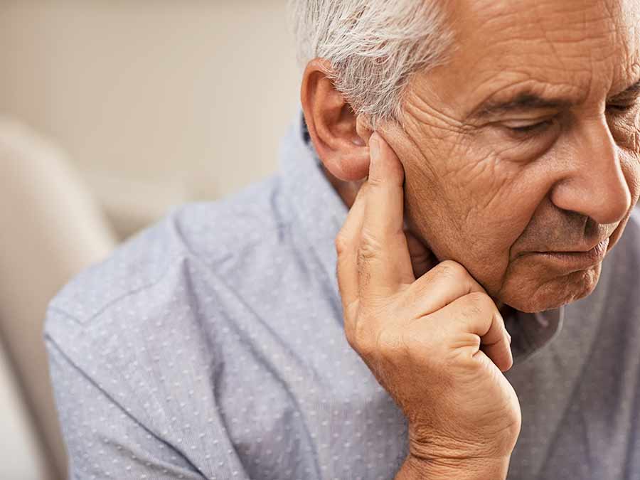 Do not ignore the signs of age related hearing loss - get help and advice from True Tone Hearing Care in Northern Ireland - here a gentleman is holding his ear as his hearing is not at its best