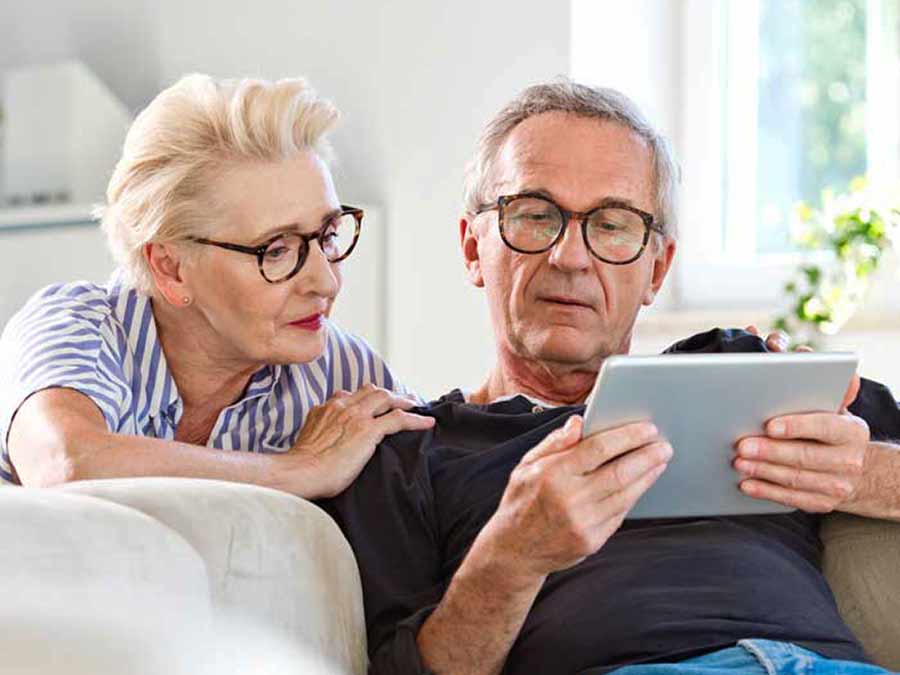 Recognise the symptoms of age related hearing loss with advice from True Tone Hearing Care Northern Ireland - here a couple are reading the True Tone Hearing website hearing loss page on a tablet device.